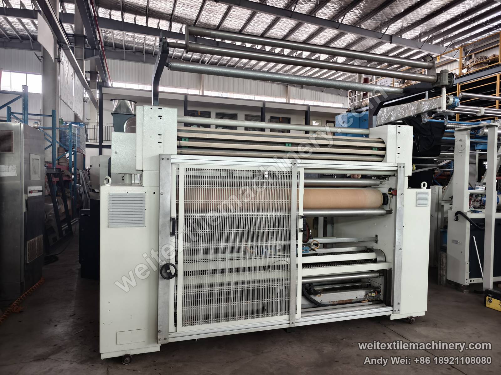 Used Bianco Tramatex SP04 pin-wheel weft straightener, front view with mesh guard doors, top guide rollers and film-wrapped rolls