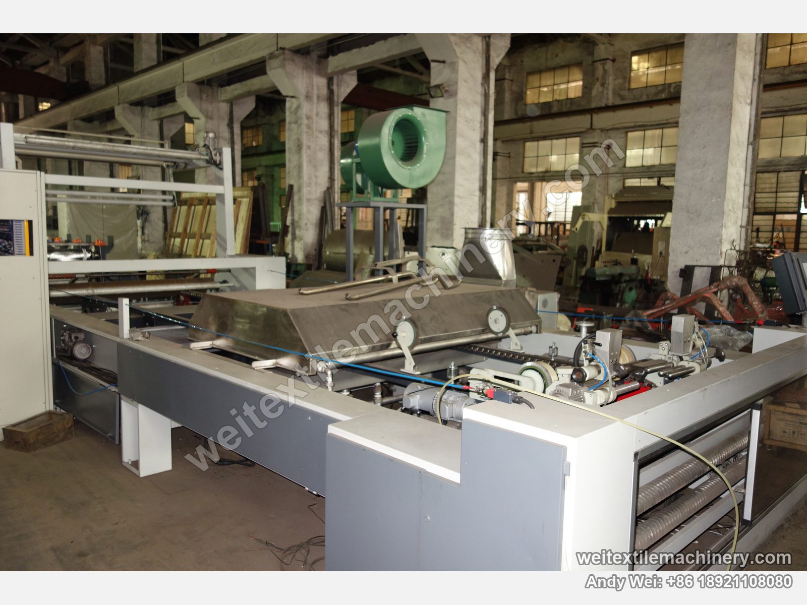 Used CoMaR SIRIO pin-chain steaming-shrinking machine, side view of the stainless steam hood, fan, pin-chain rail and pinning brush wheels