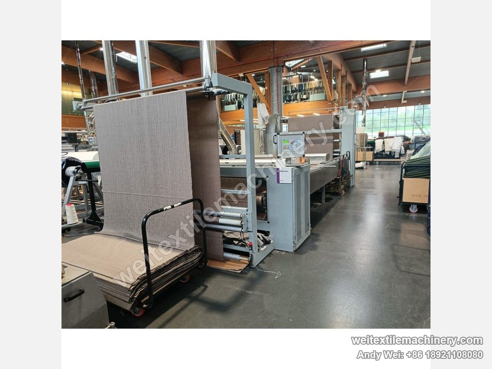 Used CoMaR VAPORAMA belt-type steaming-shrinking machine, mid view with touch screen and cabinet at centre, fabric trolley in the foreground