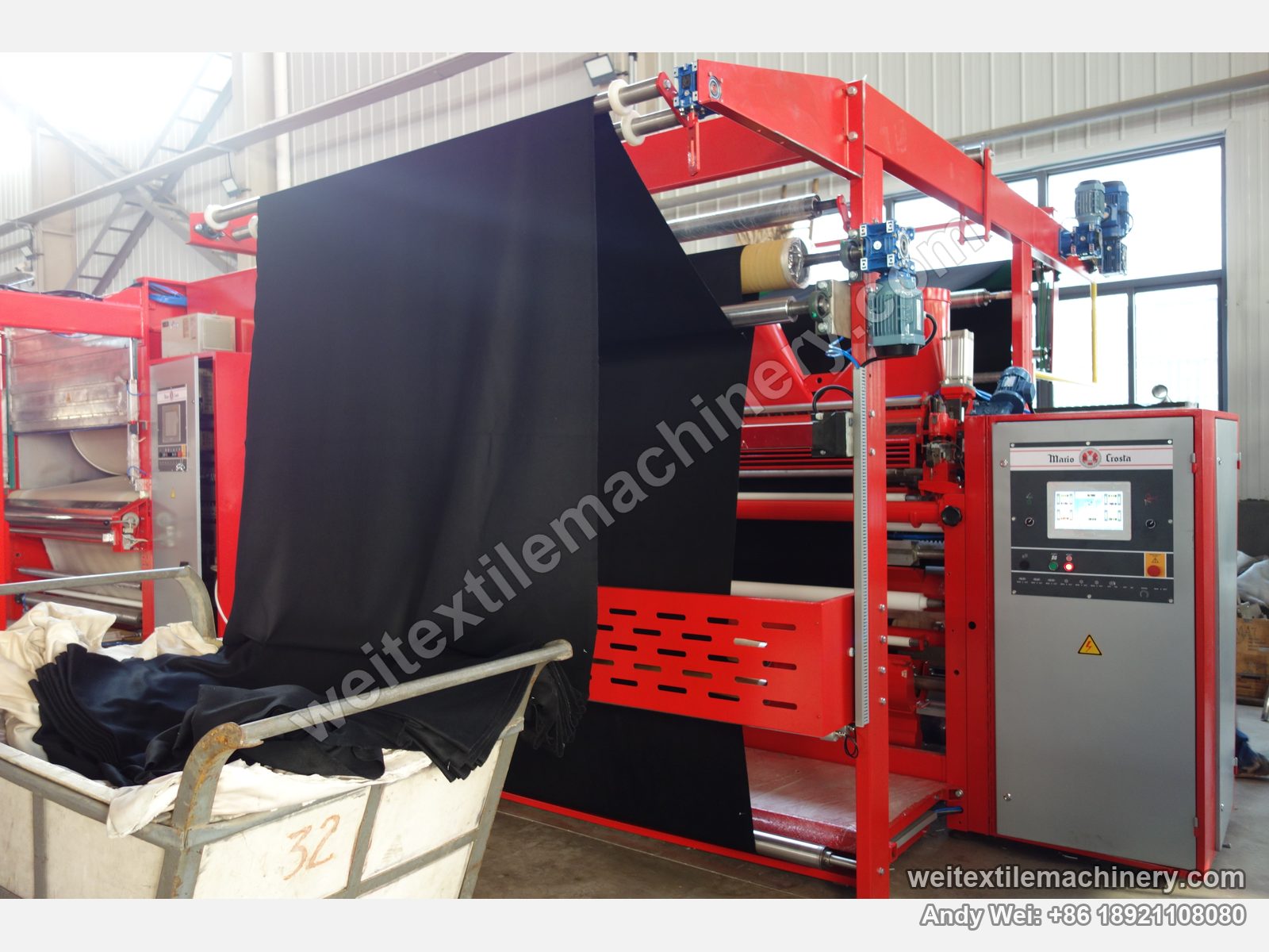 Used Mario Crosta SSC/a shearing machine running with fabric, black cloth falling from the machine into the trolley, Mario Crosta cabinet at right