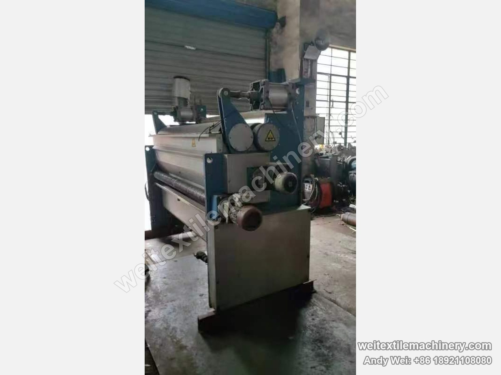 Used Monforts padder, full view with blue frame, two-roll nip, top motor and pneumatic loading cylinder