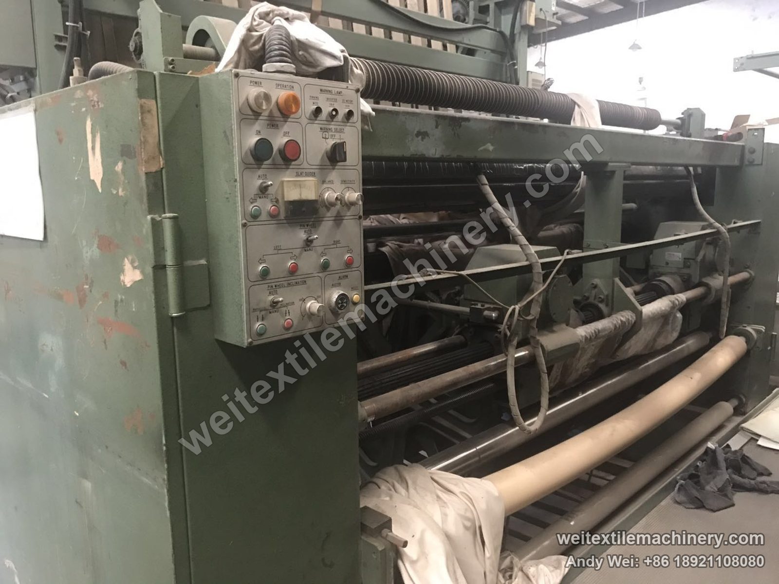 Used Tsuchiya pin-wheel weft straightener, full view with green body, English-labelled control box, top guide roll and inner rolls, cloth draped over it