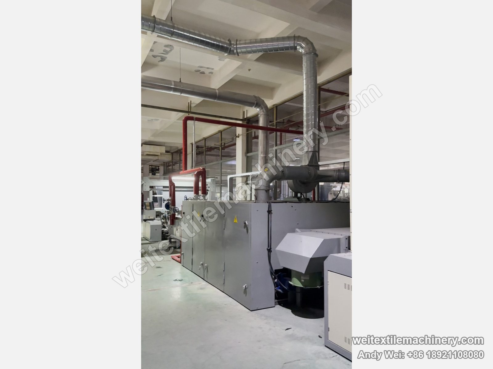 Used Unitech F2 pin-chain steaming-shrinking machine, side view with grey cabinets, exhaust ducting and blower housing