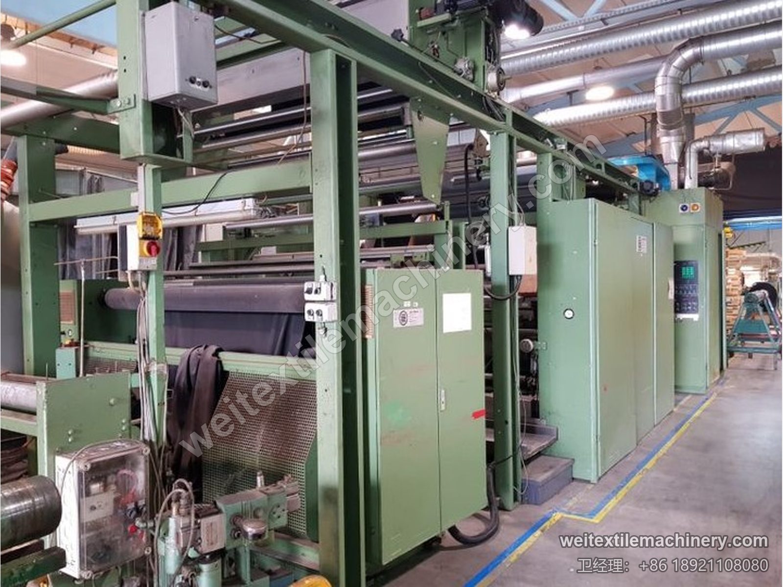 二手 M-Tec 针轮式整纬机在原厂车间，绿色机身、导布架与电控柜